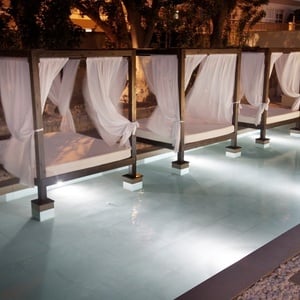 eine Reihe von Betten mit weißen Vorhängen neben einem Pool
