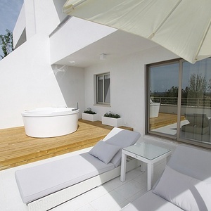 a white jacuzzi sits on a balcony with white furniture