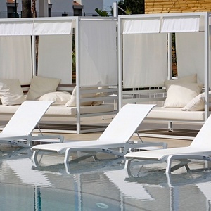 algunas tumbonas blancas están junto a una piscina