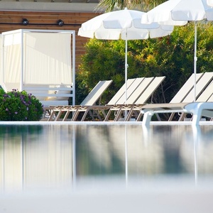 una piscina rodeada de sillas y sombrillas blancas