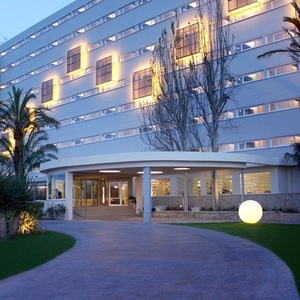 ein großes weißes Gebäude mit vielen Fenstern und Palmen