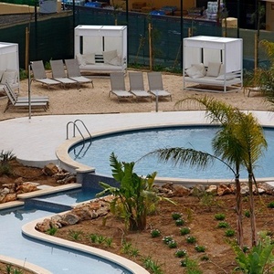 una gran piscina rodeada de muebles y palmeras