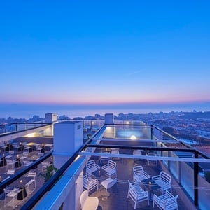 una terraza con mesas y sillas y una vista del océano al atardecer