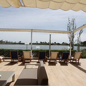 a row of chairs sit under a canopy overlooking a lake