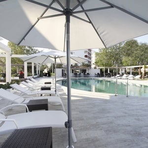 una piscina rodeada de sillas blancas y sombrillas