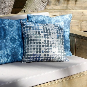 a blue and white pillow with circles on it sits on a couch