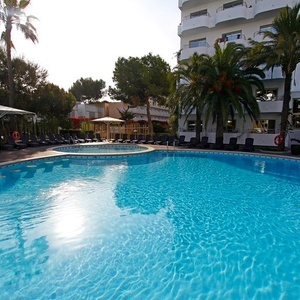 ein großer Swimmingpool vor einem Hotel mit Palmen