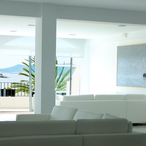 una sala de estar con sofás blancos y una pintura en la pared