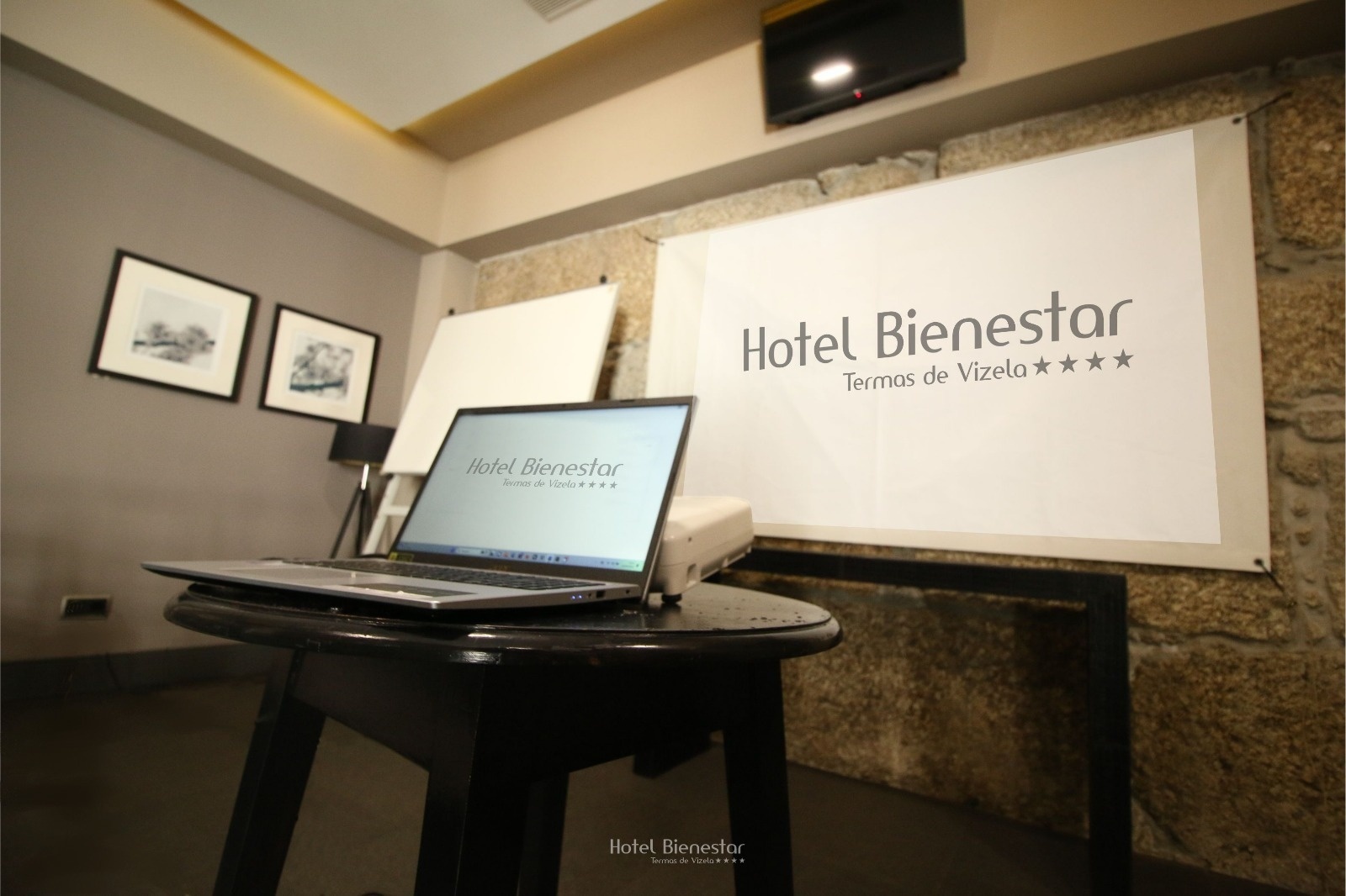 uma sala com cadeiras e uma tela que diz hotel bienestar