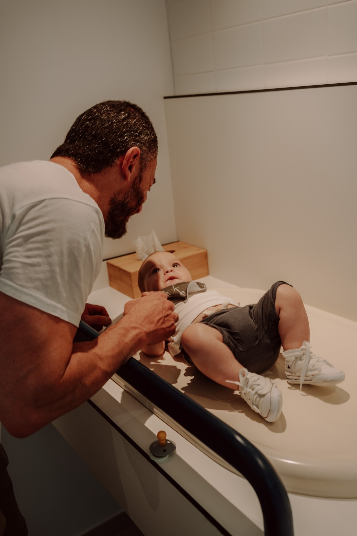 un homme regarde un bébé allongé sur une table à langer