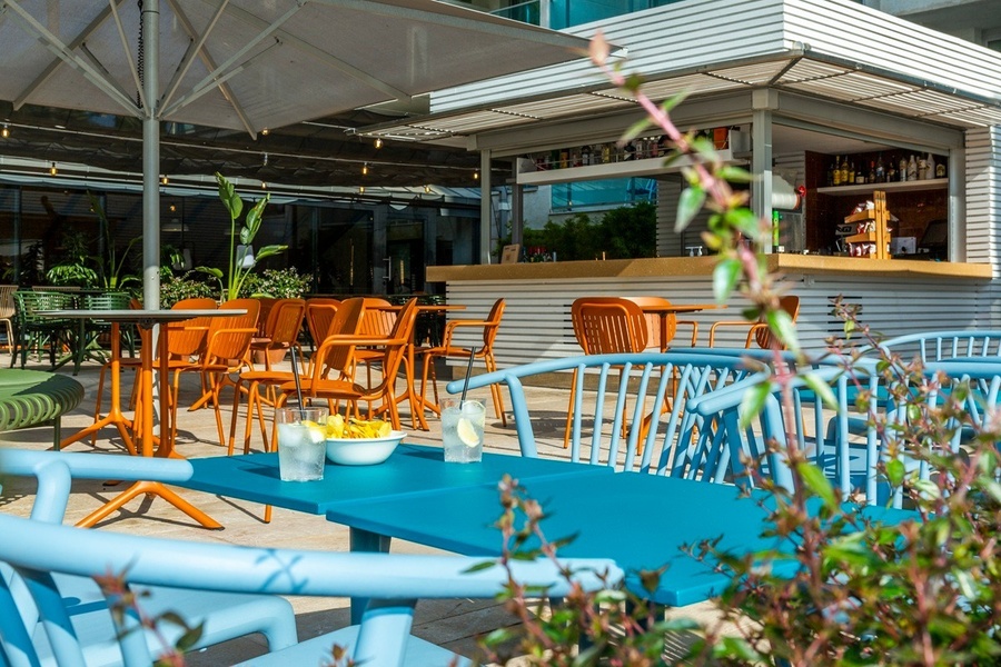 un patio con mesas y sillas y un paraguas azul