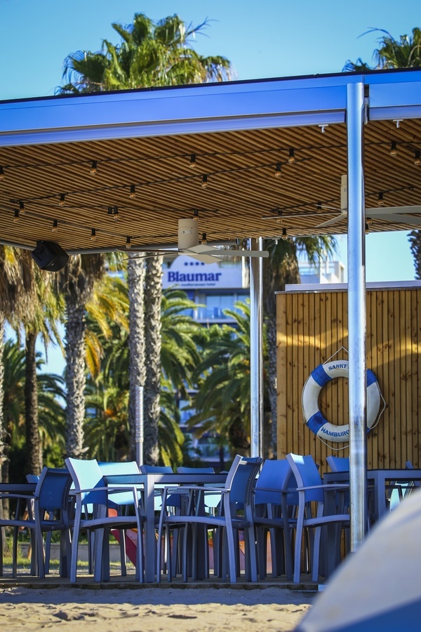 une plage avec des tables et des chaises bleues et une enseigne bleue qui dit bluuma