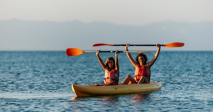dos mujeres remen en un kayak en el océano