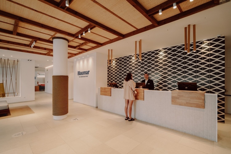 a woman stands at a reception desk in a room that says baumar