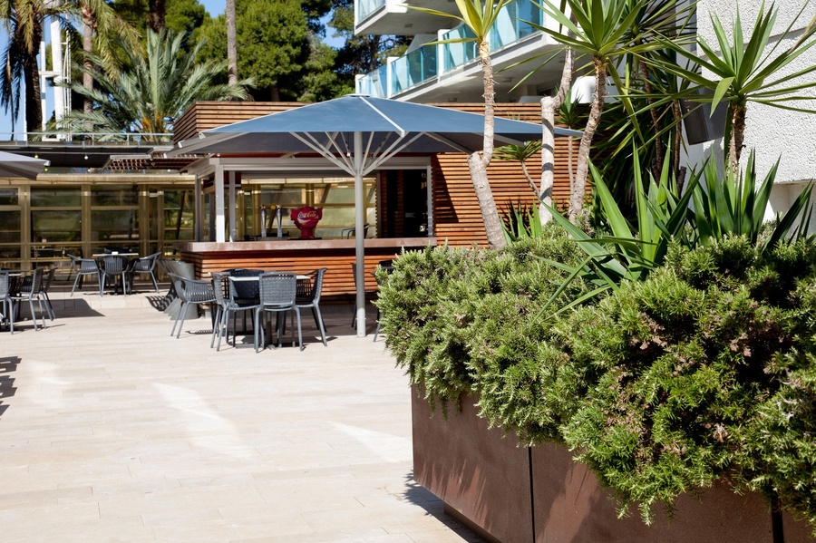 un patio avec des tables et des chaises sous un parapluie bleu