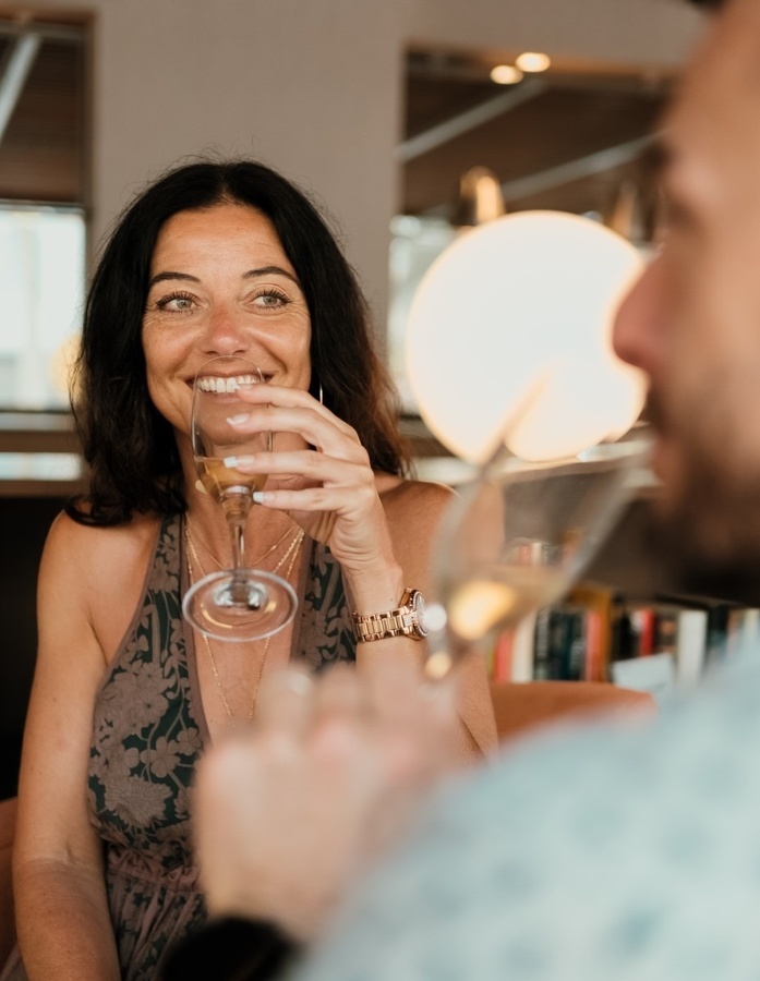 a woman is drinking a glass of wine and smiling