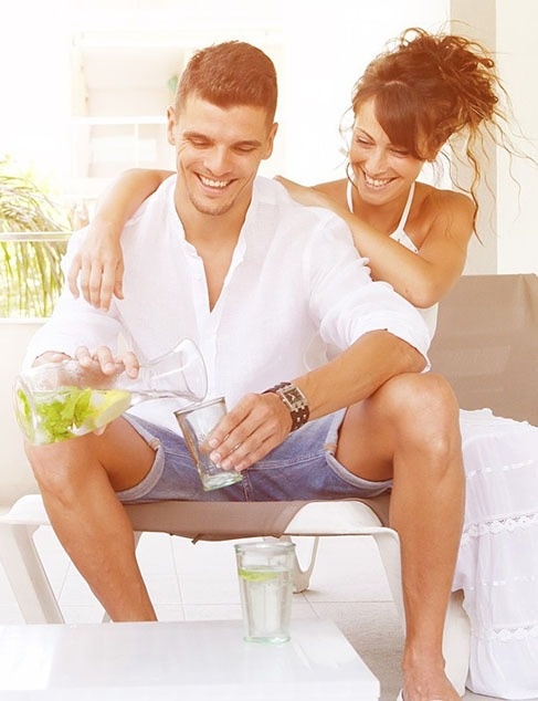 a man is pouring water into a glass while a woman looks on