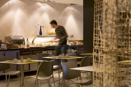 un hombre camina por un comedor lleno de mesas y sillas