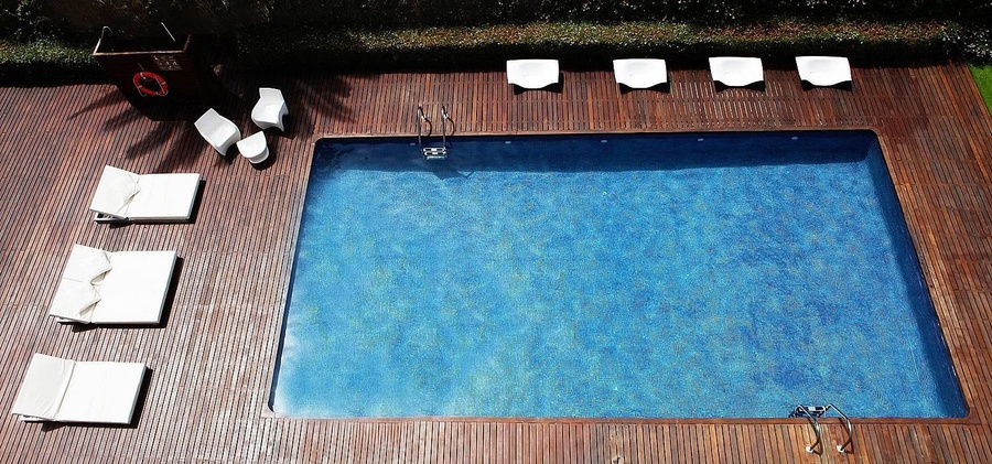 una piscina rodeada de sillas y muebles en un piso de madera