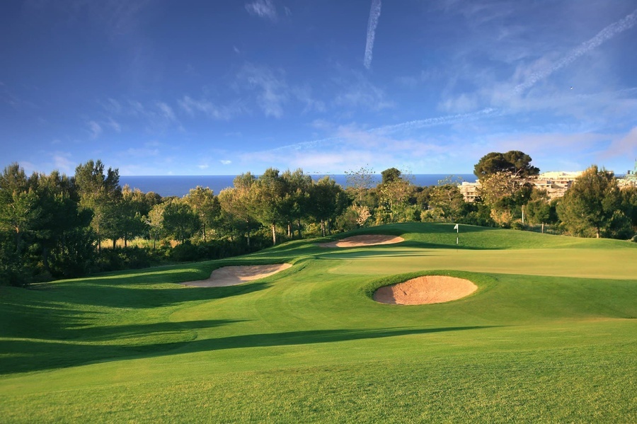 a golf course with a green and a sand bunker