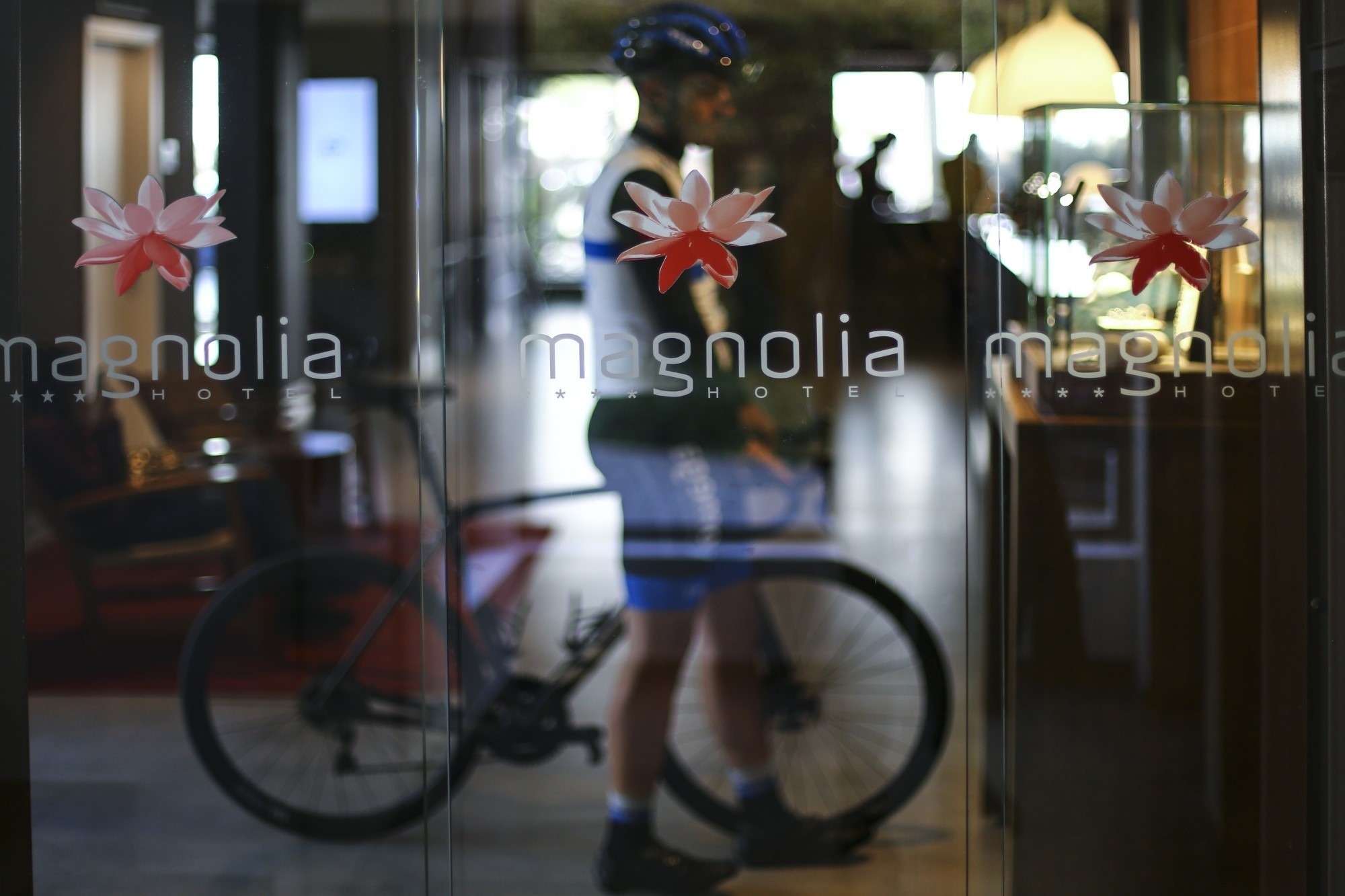 un hombre con una bicicleta frente a la puerta del hotel magnolia