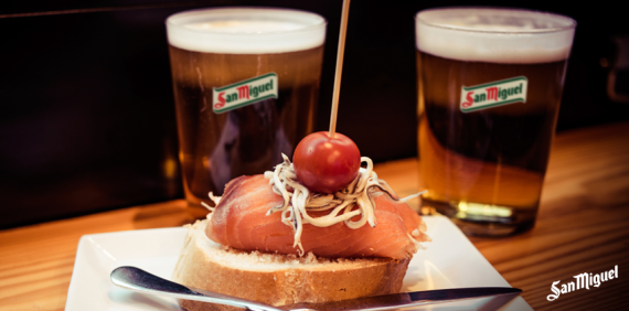 dos vasos de cerveza san miguel junto a un plato de comida