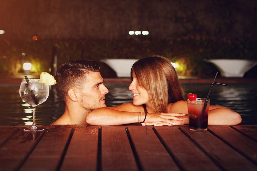 un hombre y una mujer se miran en una piscina con bebidas