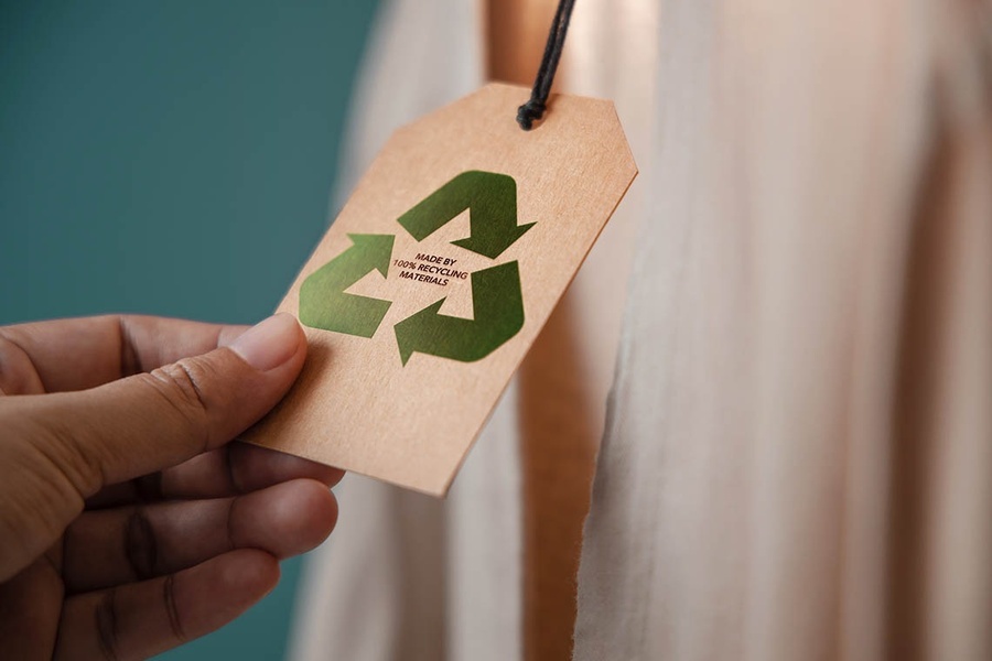 eine Person hält ein Etikett mit einem recyclingsymbol darauf