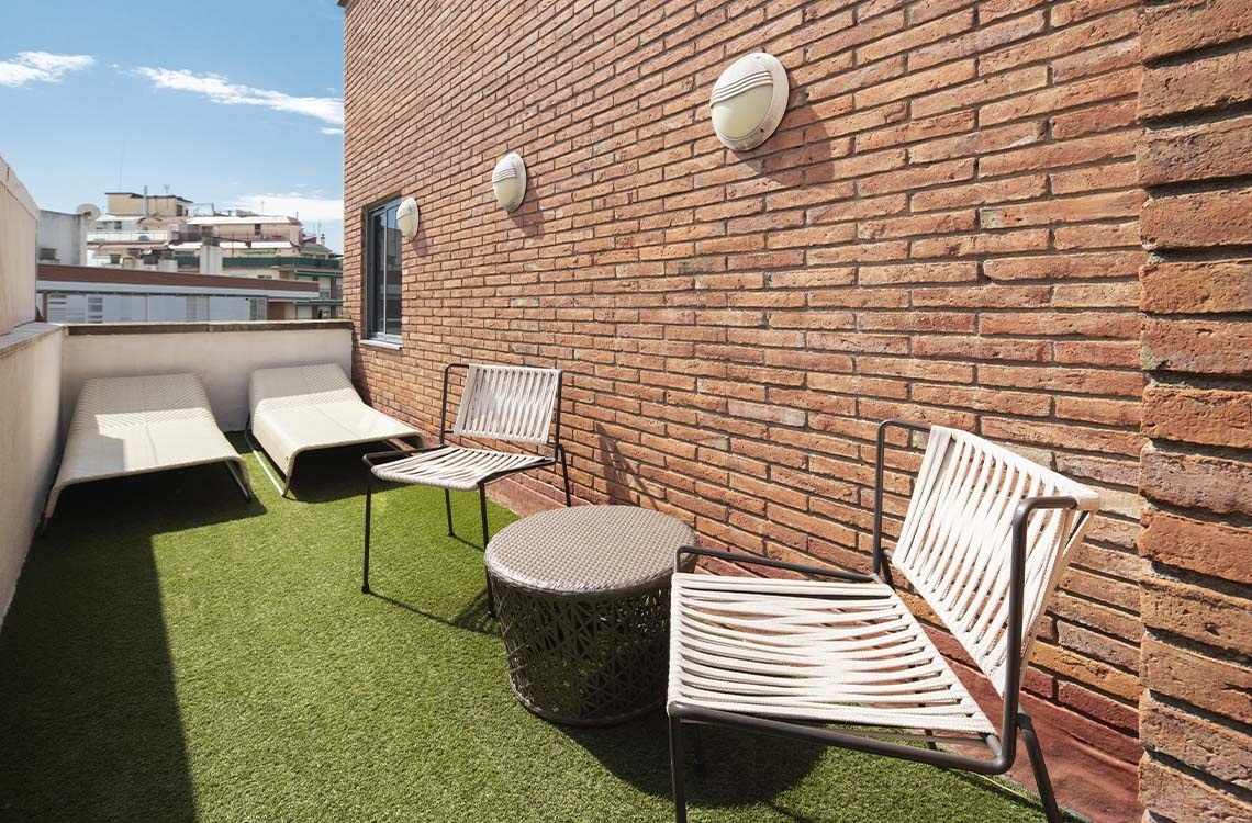 Bohemian Hotels balcony with lounge chairs, coffee table, and brick wall.