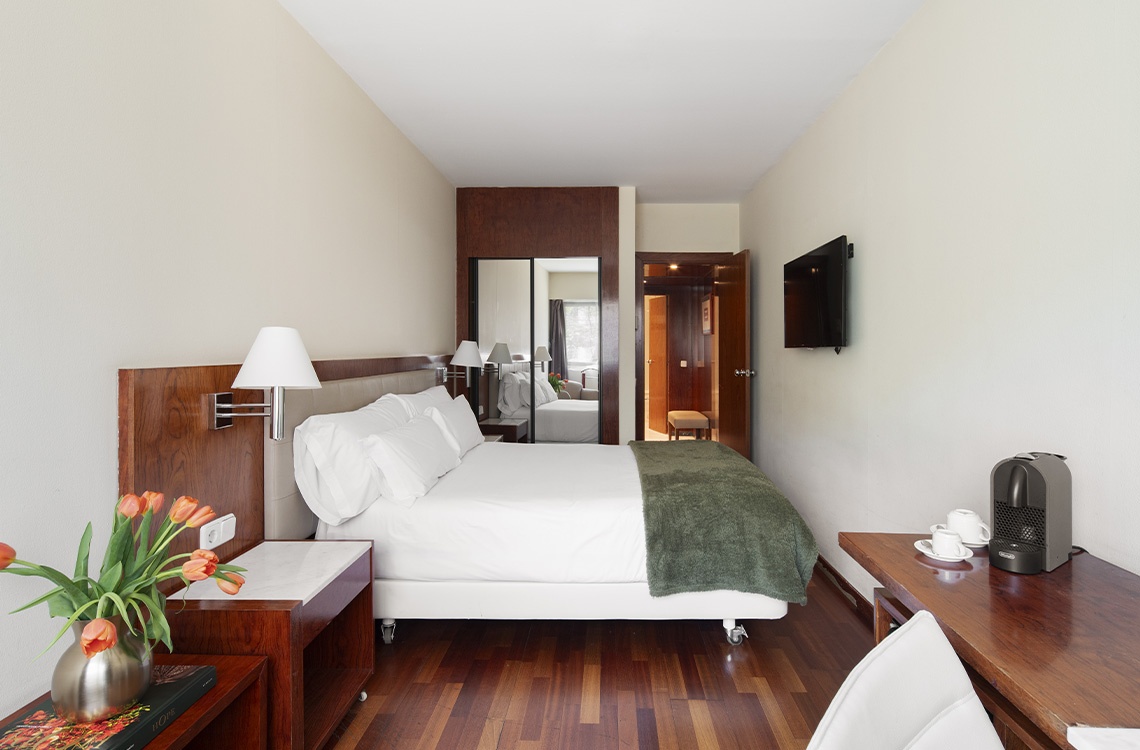 Chic hotel room with a plush bed, tulips, and modern amenities. Experience Bohemian Hotels.