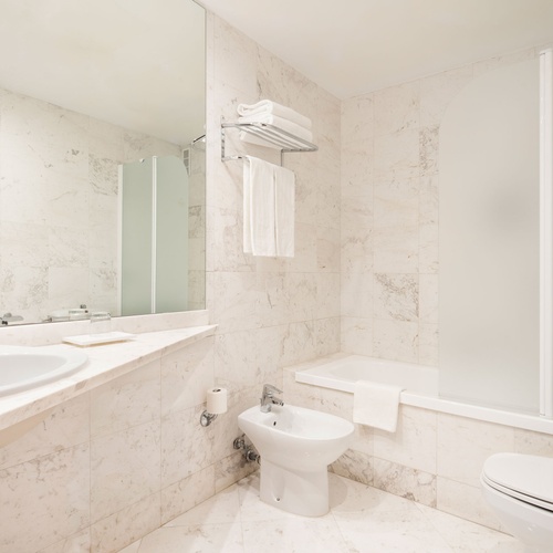 Luxurious bathroom at Bohemian Hotels with marble finishes, bidet, bathtub, and modern sink.
