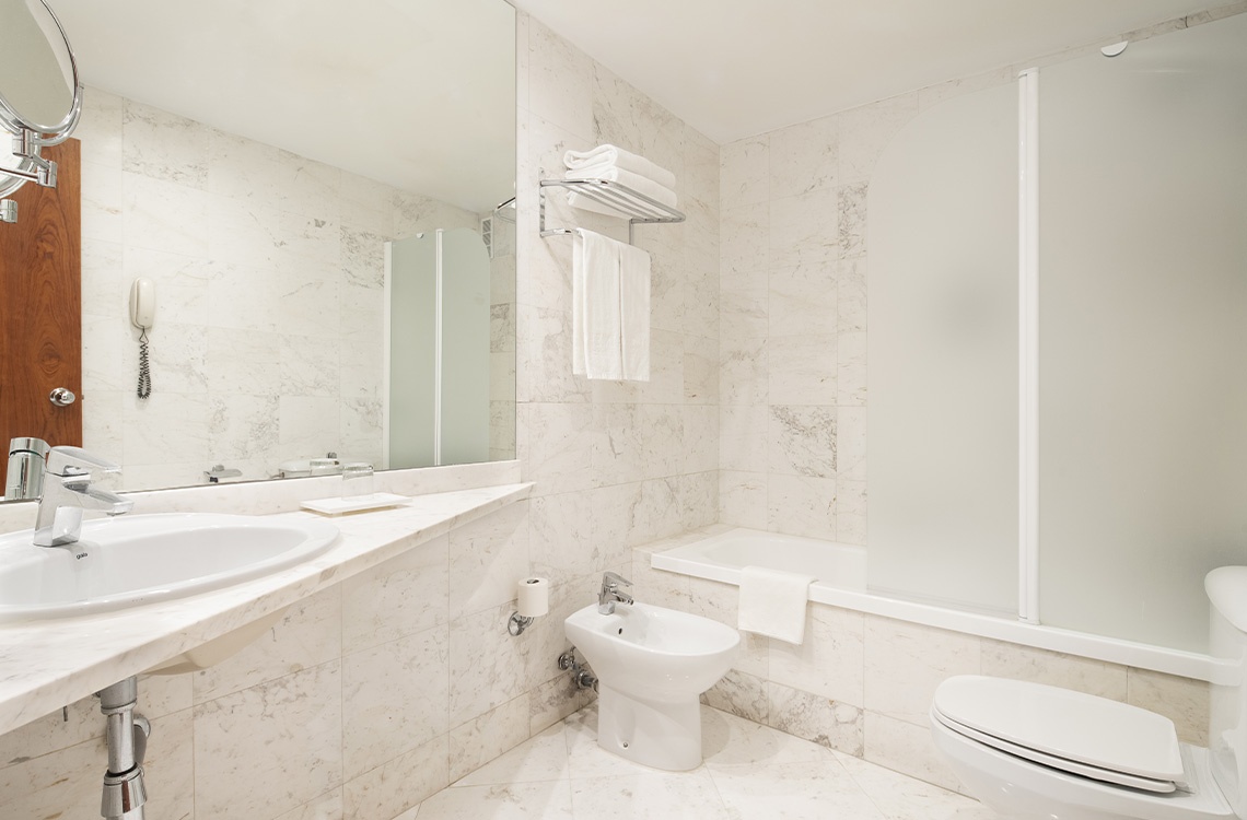 Modern hotel bathroom with bidet, bathtub, and sink. A Bohemian Hotels aesthetic.