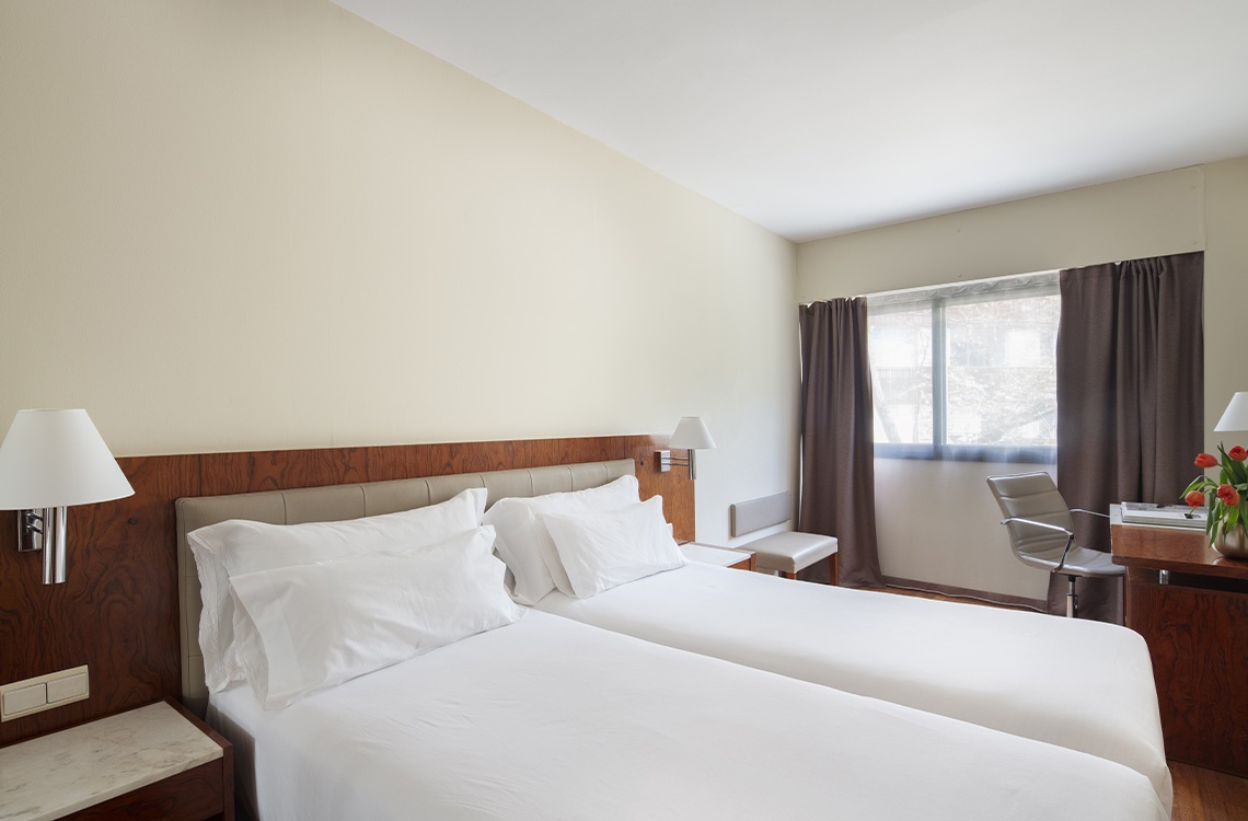 Bohemian Hotel room with two twin beds, desk, and window.