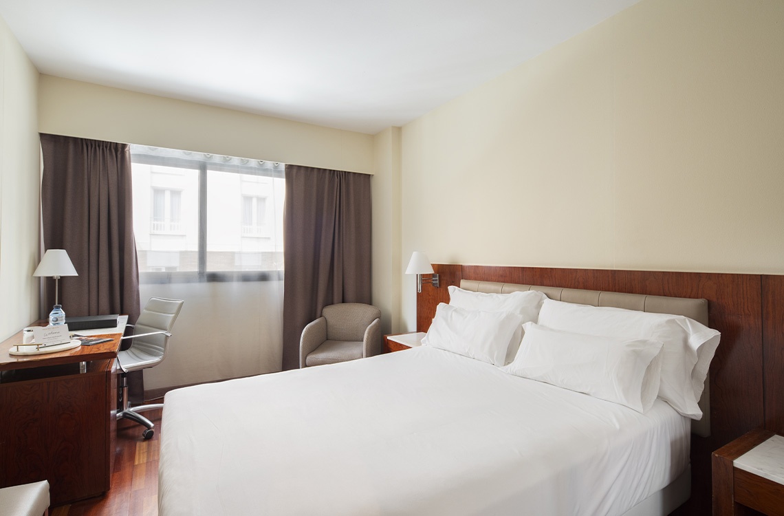 Comfortable Bohemian hotel room with a plush bed and desk.