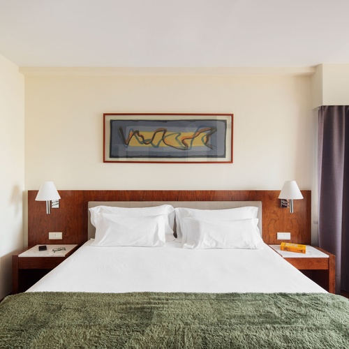 Hotel room with king-size bed, nightstand, and view of the door. Perfect for Bohemian Hotels.