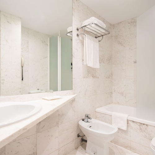 Luxurious marble bathroom in a Bohemian Hotels property, featuring a sink, bidet, and bathtub.