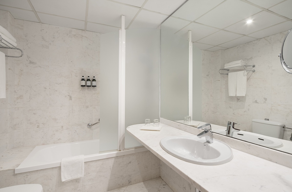 Modern Bohemian Hotels bathroom with marble tiles, bathtub, and spacious vanity with sink.