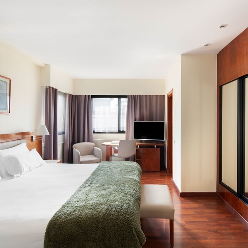 Bohemian hotel room: king bed, abstract art, desk. Perfect for a stylish and comfortable stay.