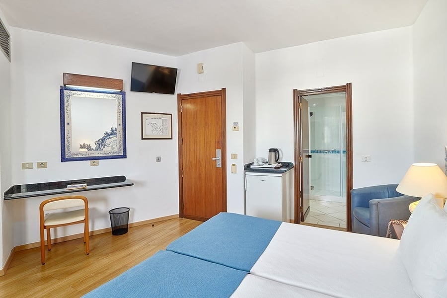 um quarto de hotel com uma cama azul e uma mesa