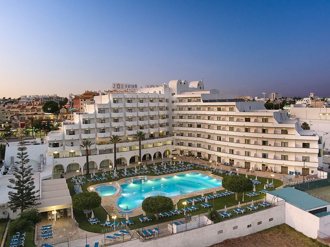 um grande hotel branco com uma grande piscina em frente a ele