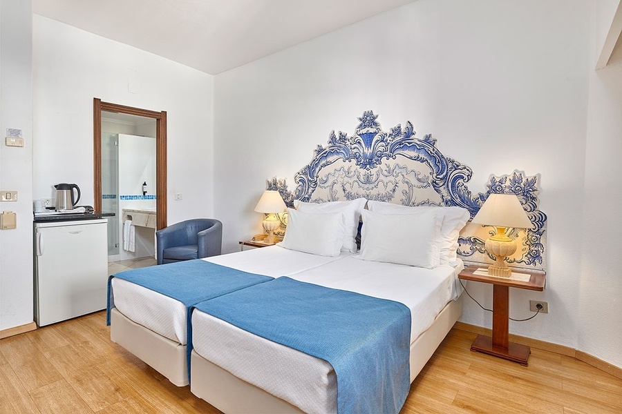 um quarto com duas camas e uma cabeceira azul e branca