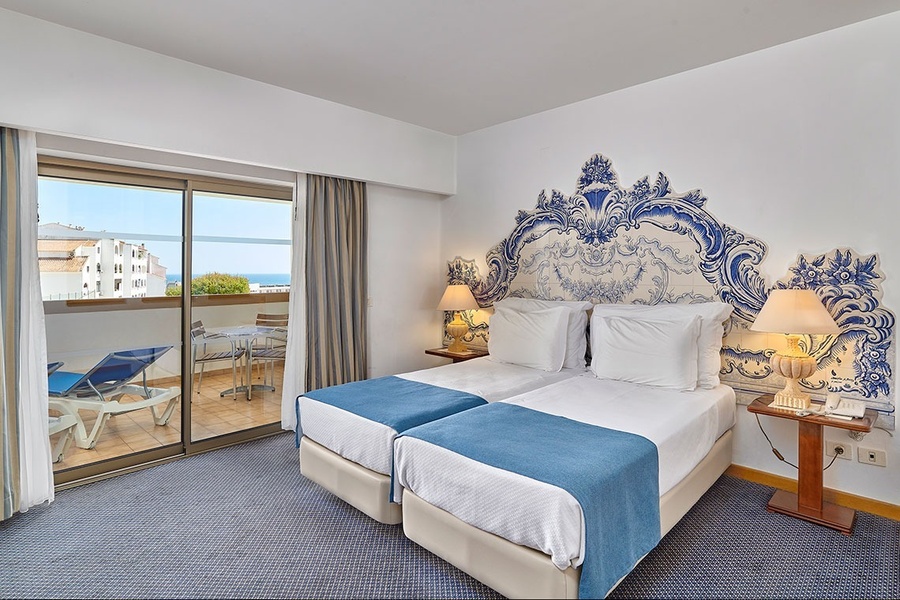 um quarto de hotel com duas camas e uma cabeceira azul e branca