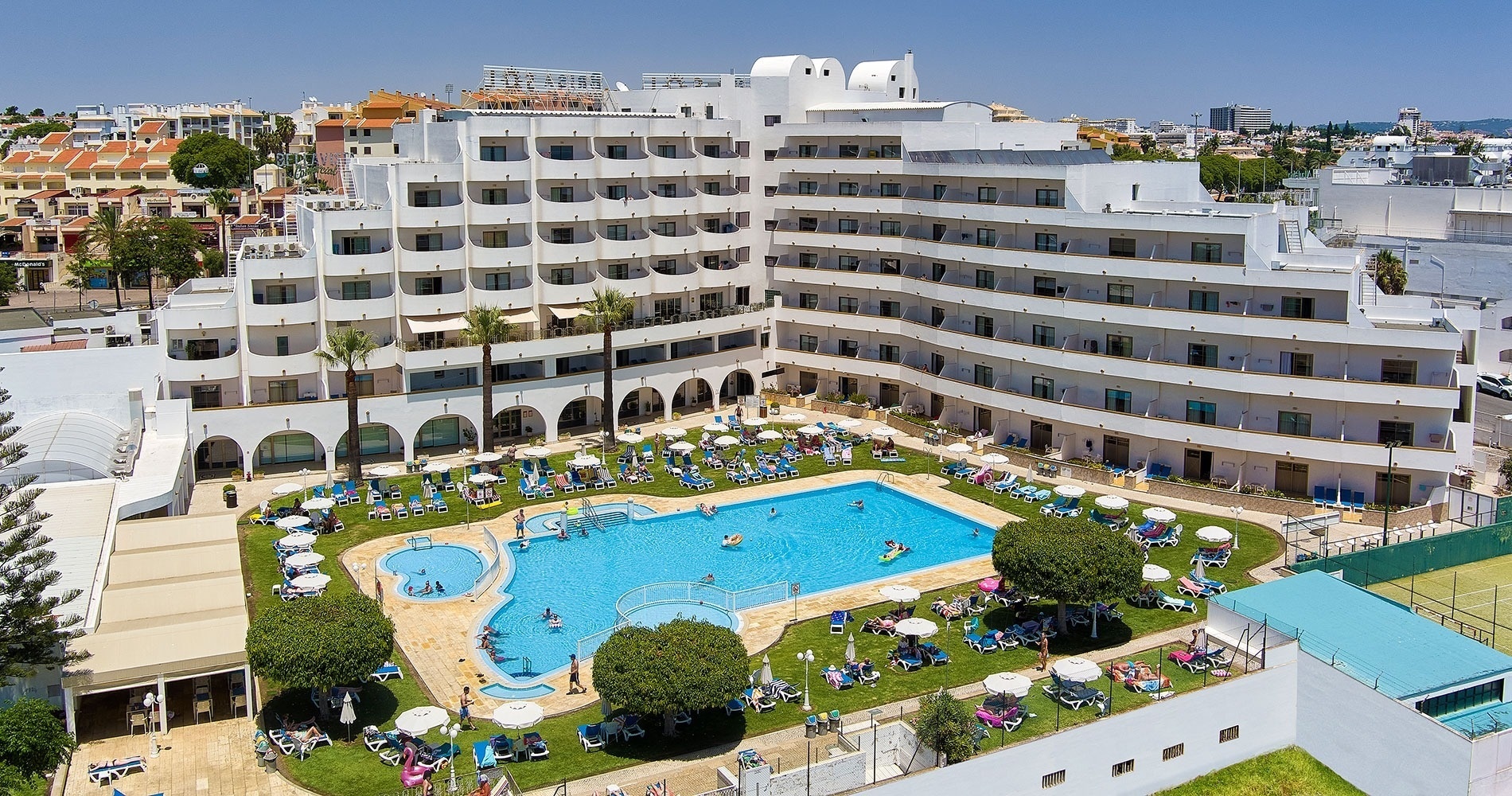 um grande hotel branco com uma grande piscina em frente a ele
