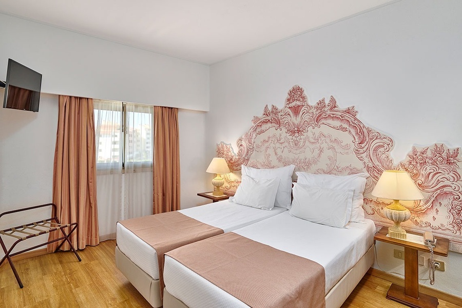 um quarto de hotel com duas camas e uma televisão