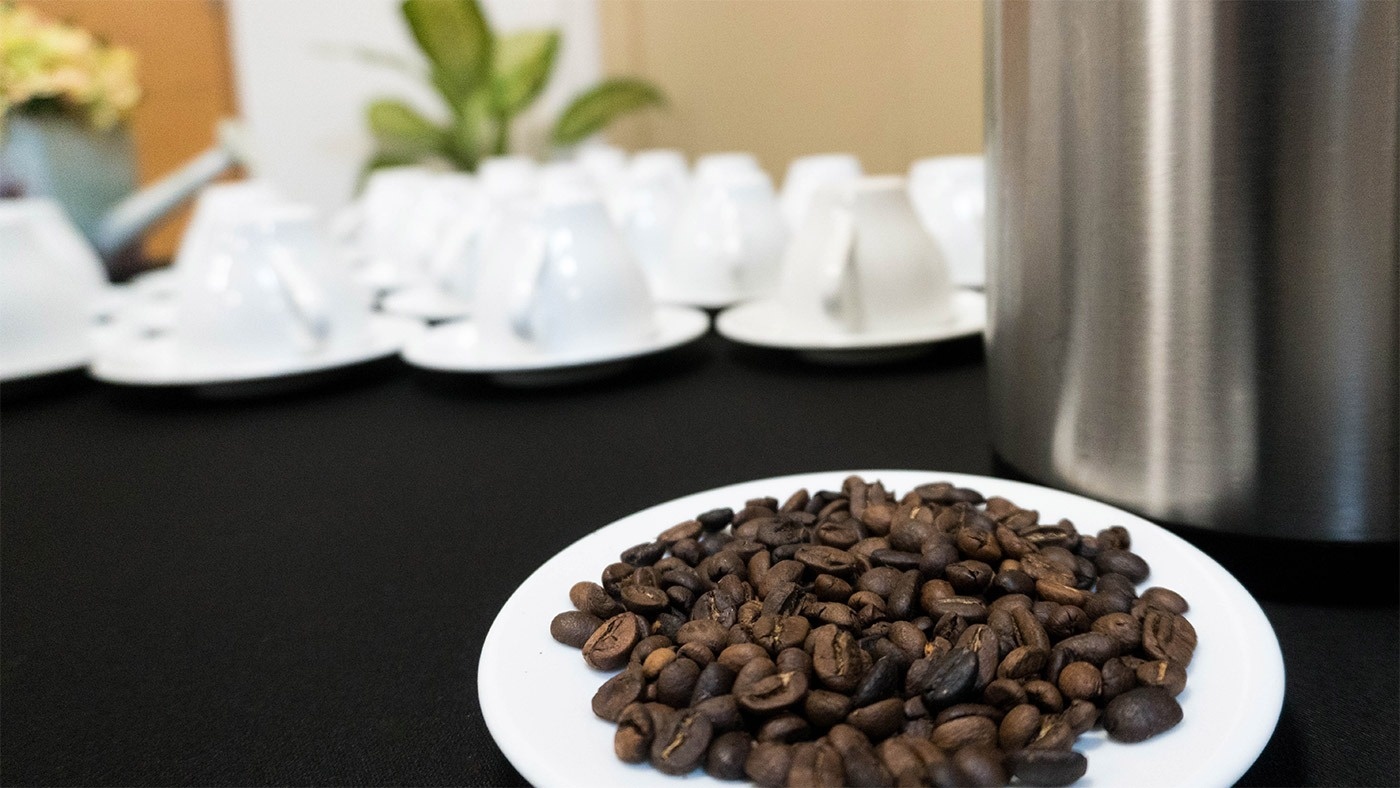 un plato blanco lleno de granos de café está sobre una mesa negra