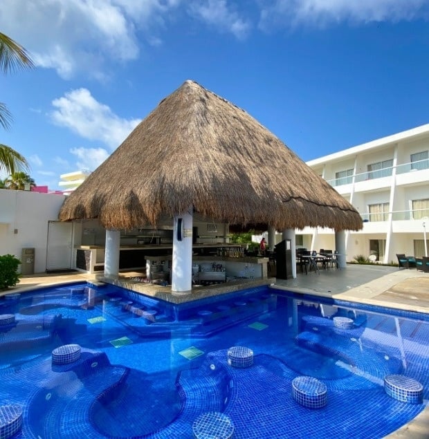 a swimming pool with a thatched roof and a bar