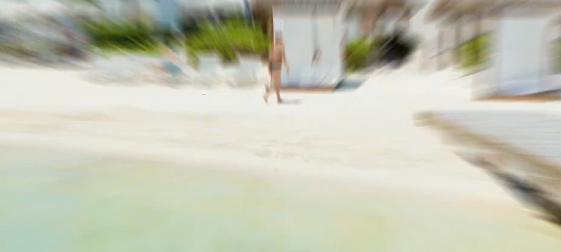 a blurry picture of a woman walking on a beach .