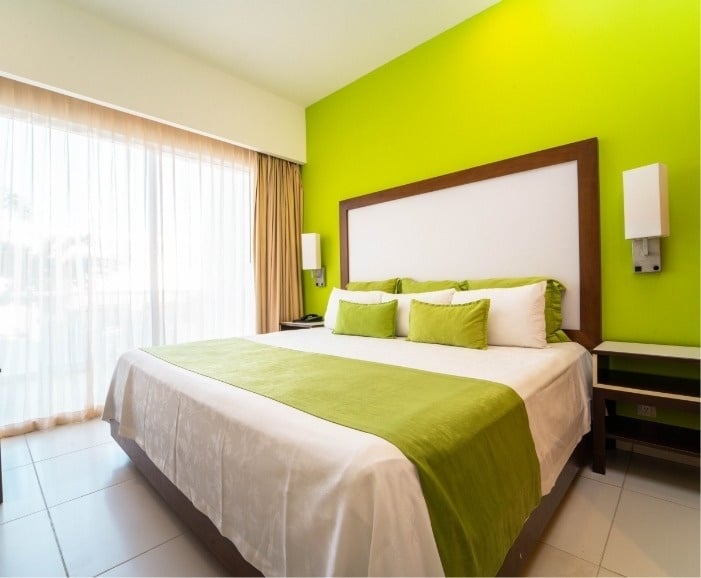 a hotel room with a bed and green walls