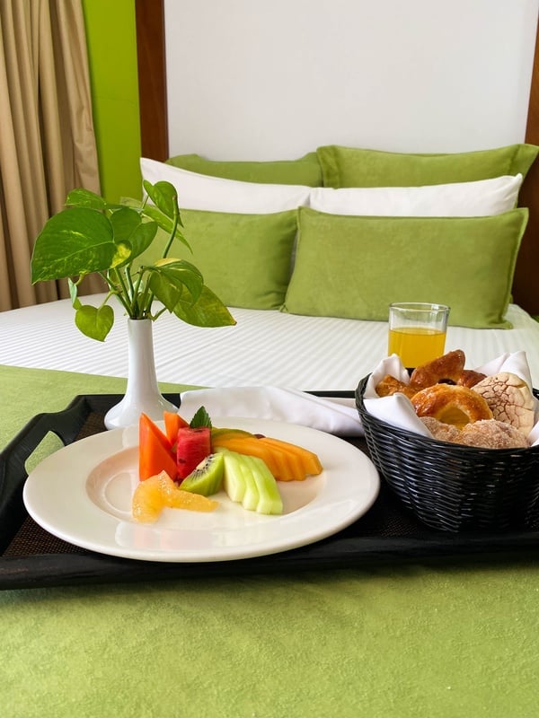 a plate of fruit and a basket of bread on a tray on a bed