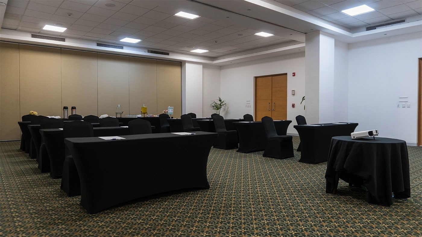 una sala de conferencias con mesas y sillas cubiertas con cubiertas negras